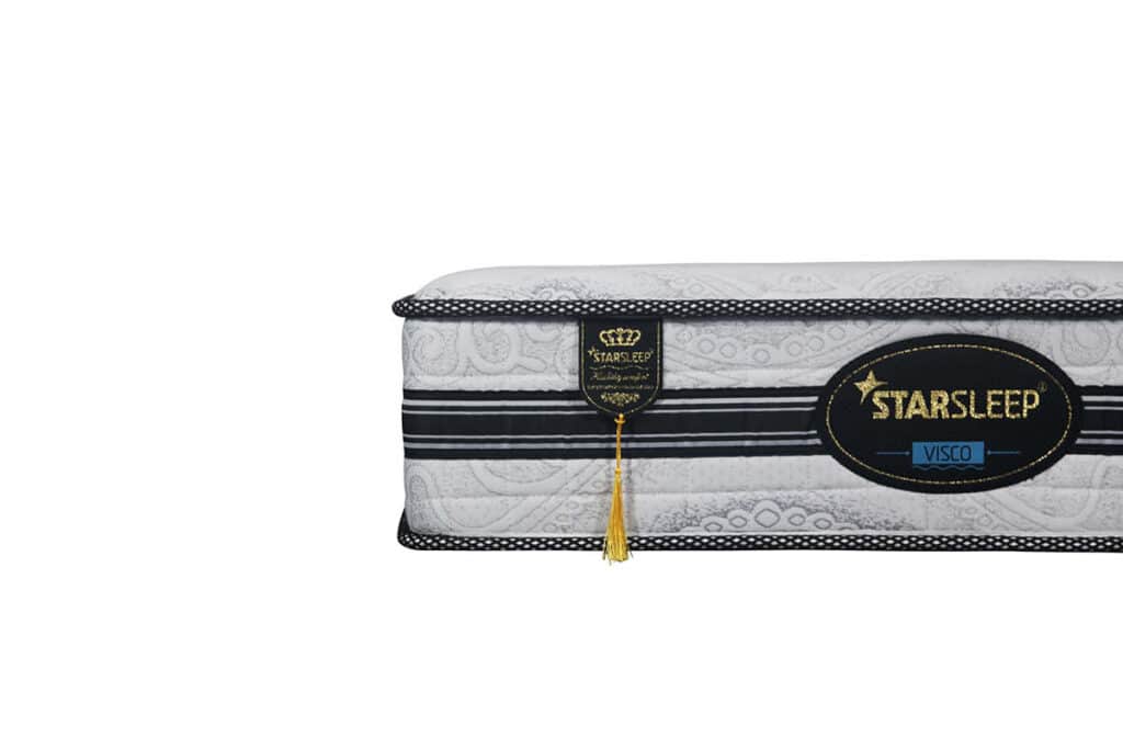בתמונה נראה צד של מזרן לבן עם פסים שחורים, ועליו תווית זהובה עם הכיתוב "STAR SLEEP".