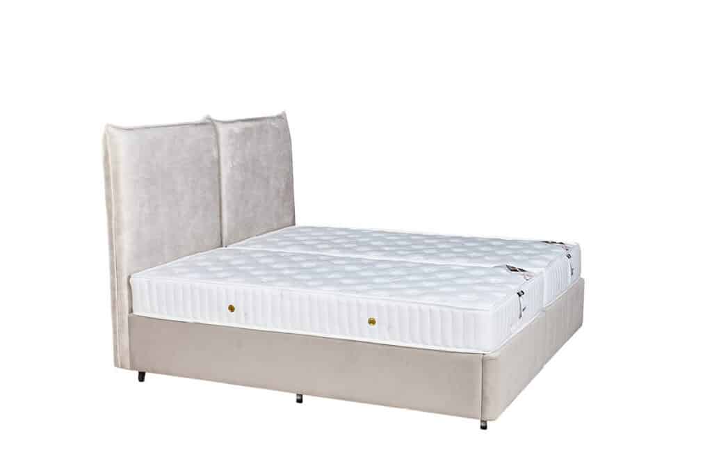 בתמונה מיטה זוגית עם ראש מיטה מרופד בד בהיר ושני מזרנים לבנים נפרדים.